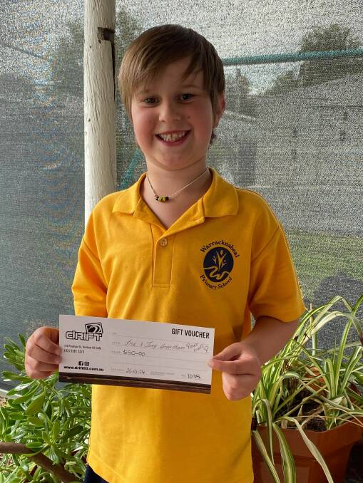 THANKS: Jayden Moloney standing with a $50 Drift 83 voucher, which will be gifted to the bike's new owner by Lisa and Tony Grantham to go towards a new helmet. Picture: CONTRIBUTED