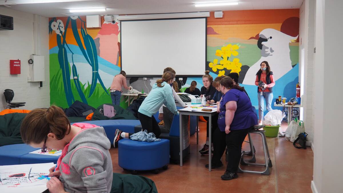 DESIGNING THE FUTURE: Young people hard at work designing hoodies under the Station's mural wall - which was also painted by youth attending the Station. Picture: ALEX BLAIN