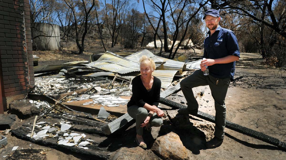 Lynda and Drew Sutherland on the ruins of part of their Roses Gap Recreation Centre in 2014, after it was hit by the January Grampians Bushfires. 