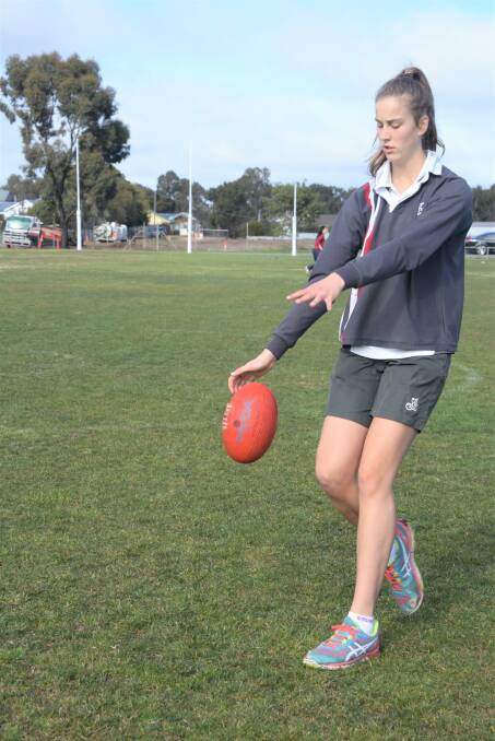 Future AFLW star Maggie Caris kicks the ball during the football clinic program. 