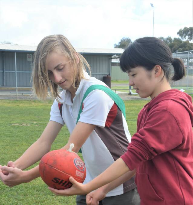 Corey Aristides teaches Hiroka Sodeyama how to correctly hand ball the football.