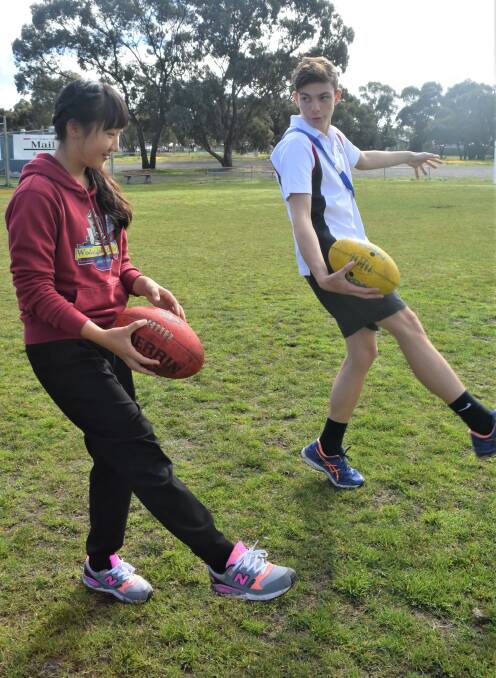 Year nine student Aiden O'Connor teaches Shiori Sugai the correct technique when kicking a football.